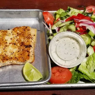 Grilled Mahi Mahi salad featuring fresh mixed greens, tomatoes, onions, cucumbers, red bell peppers and cilantro-ranch dressing.