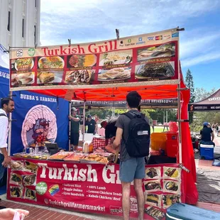 a man standing in front of a food stand