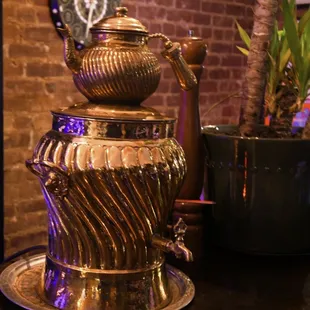 a gold teapot on a silver plate