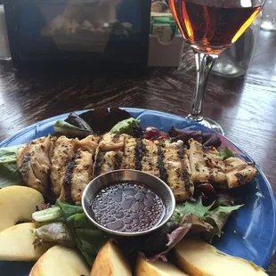 a plate of chicken, apples, and salad