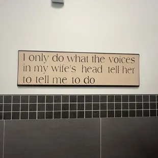 a bathroom with a sign that says only do what the voices in my wife&apos;s head tell her to