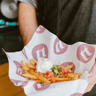 a person holding a basket of fries