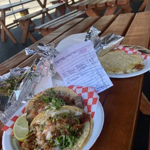 Spicy pork/lengua tacos @3., chicken mulita (4) under the tent at dining tables.