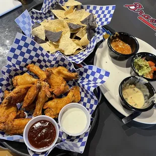 a plate of fried chicken wings and dippings