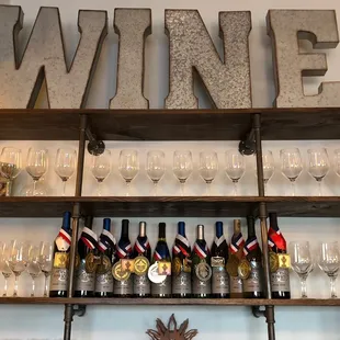 a shelf of wine glasses and wine bottles