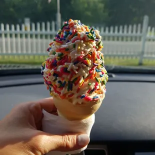 a hand holding an ice cream cone with sprinkles