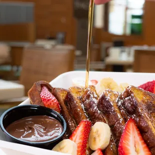 a plate of french toast with strawberries and bananas