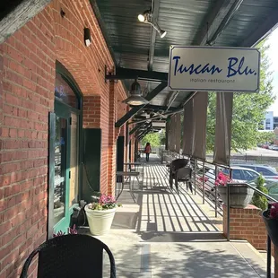 a sidewalk with tables and chairs