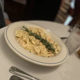 a plate of pasta with a sprig of rosemary