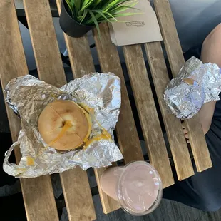 a person sitting at a table with a bagel and a drink