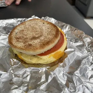 Scramble eggs with tomato, sausage, and cheese on an English muffin