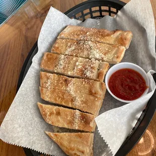 a basket of flat bread with a side of tomato sauce
