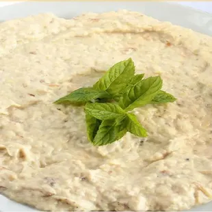 a bowl of hummusle with a sprig of mint