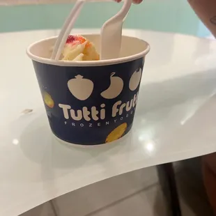 a person holding a fork and a cup of ice cream