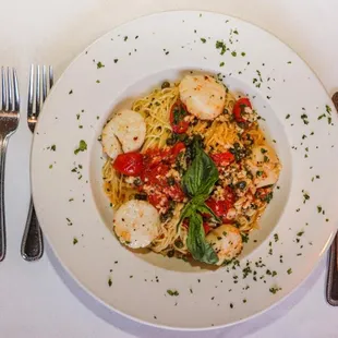 a plate of pasta with scallops and tomatoes