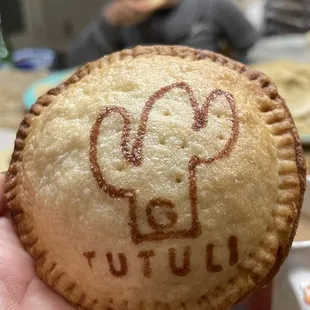 a hand holding a pastry with a drawing on it