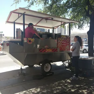 a woman standing next to a food cart