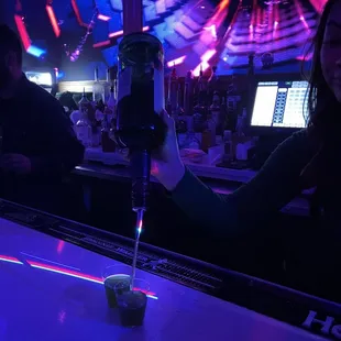 a woman pouring a drink at a bar