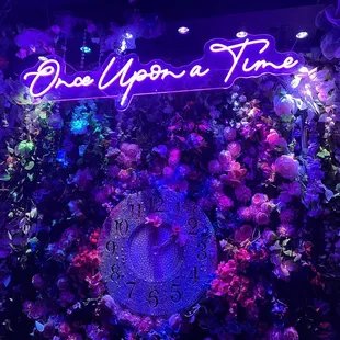 a neon sign with flowers and a clock