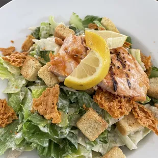 a plate of salad with salmon and croutons