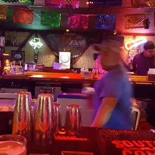 a bartender at a bar with neon signs