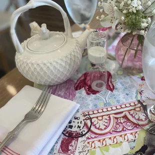 a table setting with a teapot, glassware, and napkins