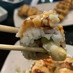 a closeup of a piece of sushi with chopsticks