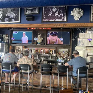 people sitting at the bar watching televisions