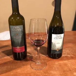 two bottles of wine and a glass