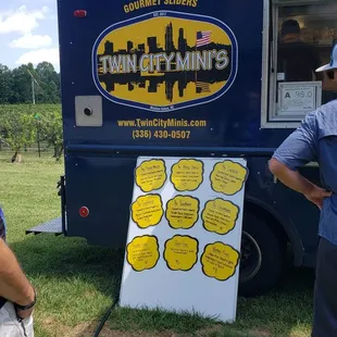two people standing in front of a food truck