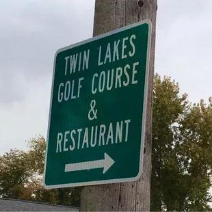 a street sign for twin lakes golf course and restaurant