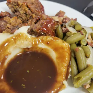 a plate of meat, mashed potatoes, green beans, and gravy