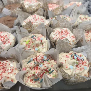 a tray of cupcakes with white frosting and sprinkles