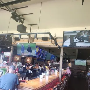 a bar with several televisions hanging from the ceiling