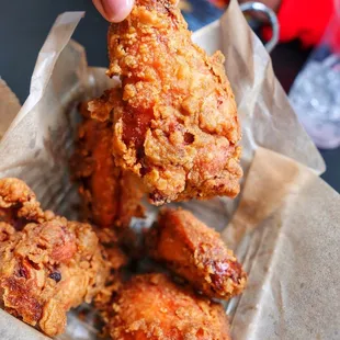 a hand holding a piece of fried chicken