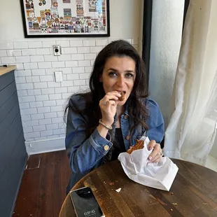 a woman sitting at a table eating a donut