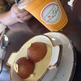 Delicious milk balls soaking in sweet syrup and a mango lassee drink