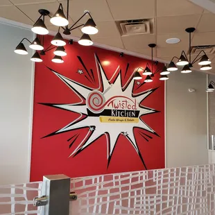 a red wall with a sign that says twisted kitchen
