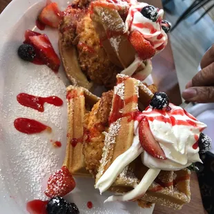 a plate of waffles topped with whipped cream and berries