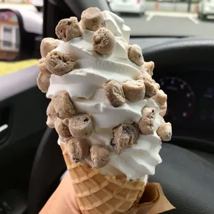 a hand holding a cone of cereal ice cream