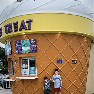 two children standing in front of a large ice cream cone