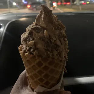 a hand holding a cone of ice cream