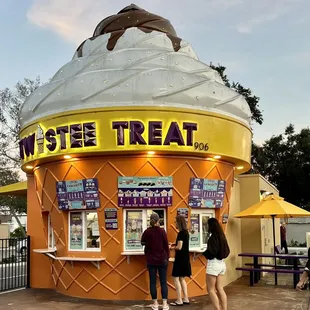 two people standing in front of an ice cream cone