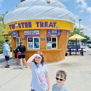 two children standing in front of a ice cream shop