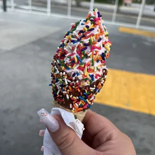 Fancy cone with black cherry ice cream and sprinkle dipped.