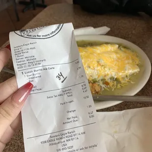 receipt stating i ordered a red chili burrito, behind is the green chili burrito they gave me.