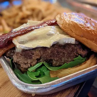 The Burger. $15. Certified Angus beef (pink or done), melted brie, bacon, fig jam, arugula, balsamic red onions, brioche bun, side of fries.