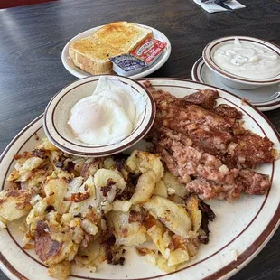 Corned beef hash with poached eggs and a side of gravy.