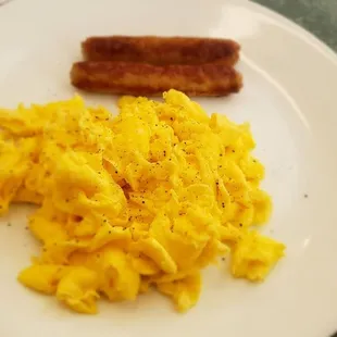 scrambled eggs and bacon on a plate