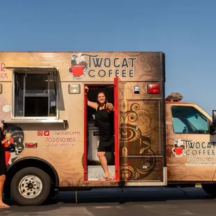 a woman standing in the doorway of a coffee truck